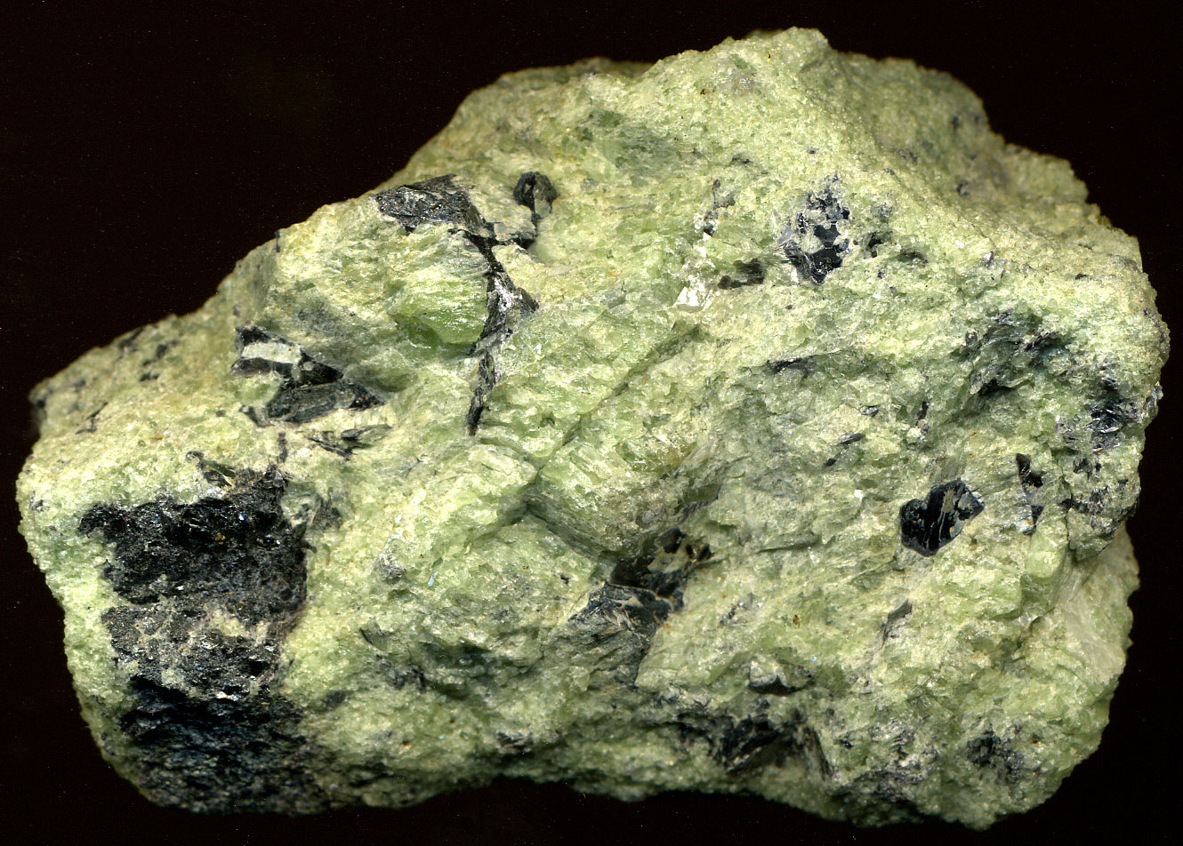 Photo of a piece of dunite, a greenish chunk of rock.