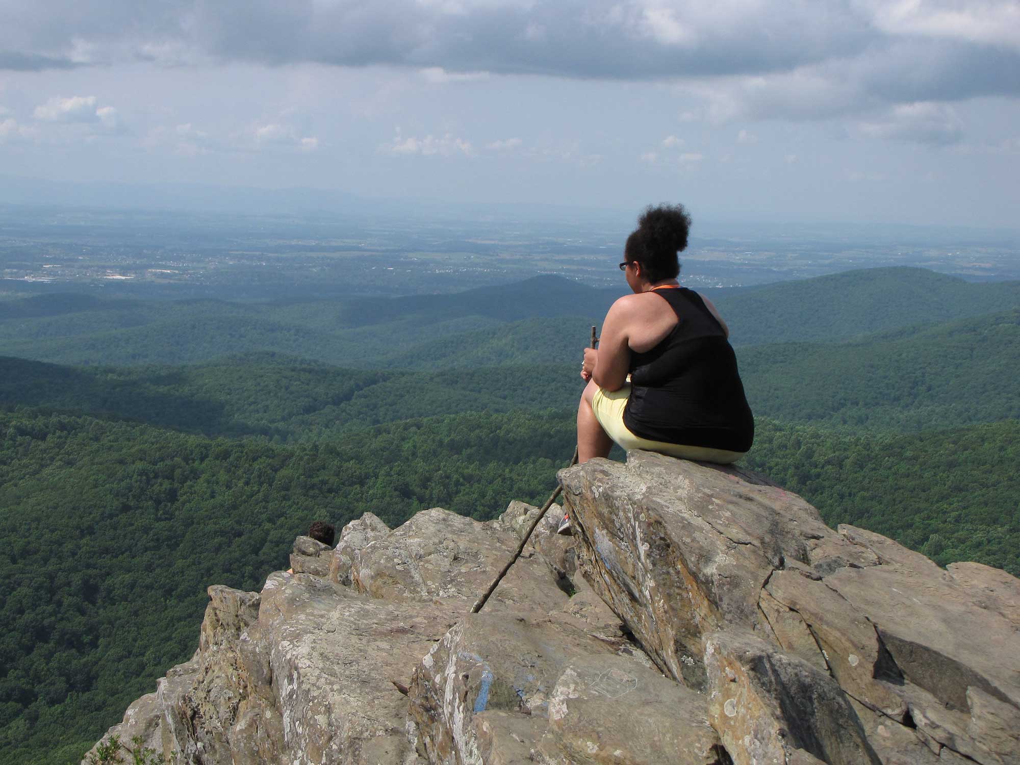 Photograph of a woman sitting on Humpback Rock, overlooking the Shenandoah Valley.