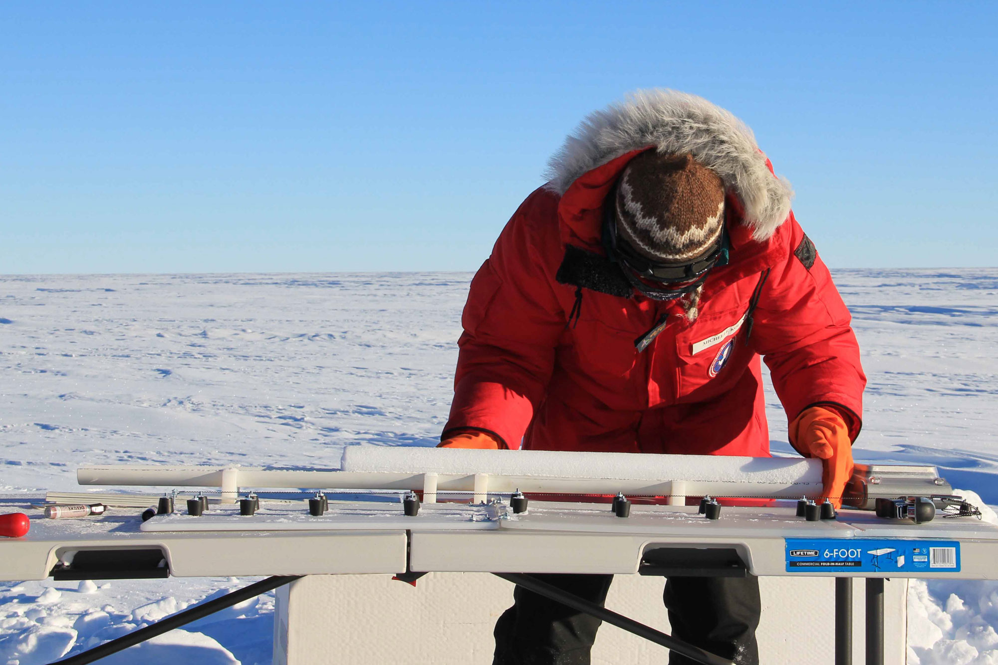 Photograph of a researcher measuring an ice core in Antarctica.