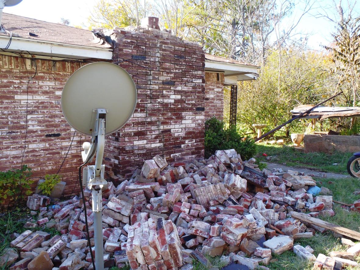 Photo of a house in Oklahoma which has been damaged by an induced earthquake. A pile of bricks from a damaged chimney lies next to the house.