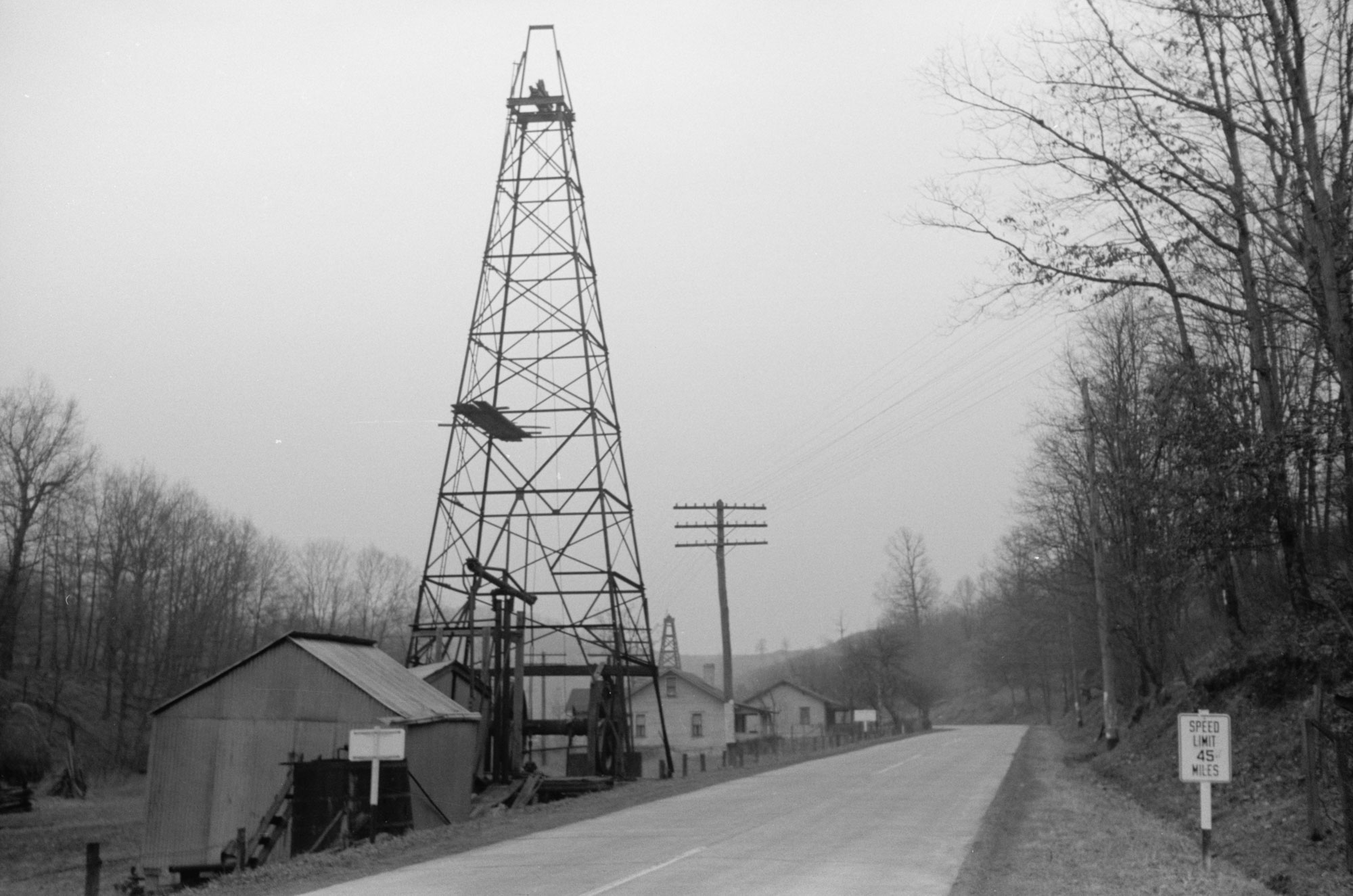 Black and white photograph of an oil derrick next to a road in West Virginia in 1940.