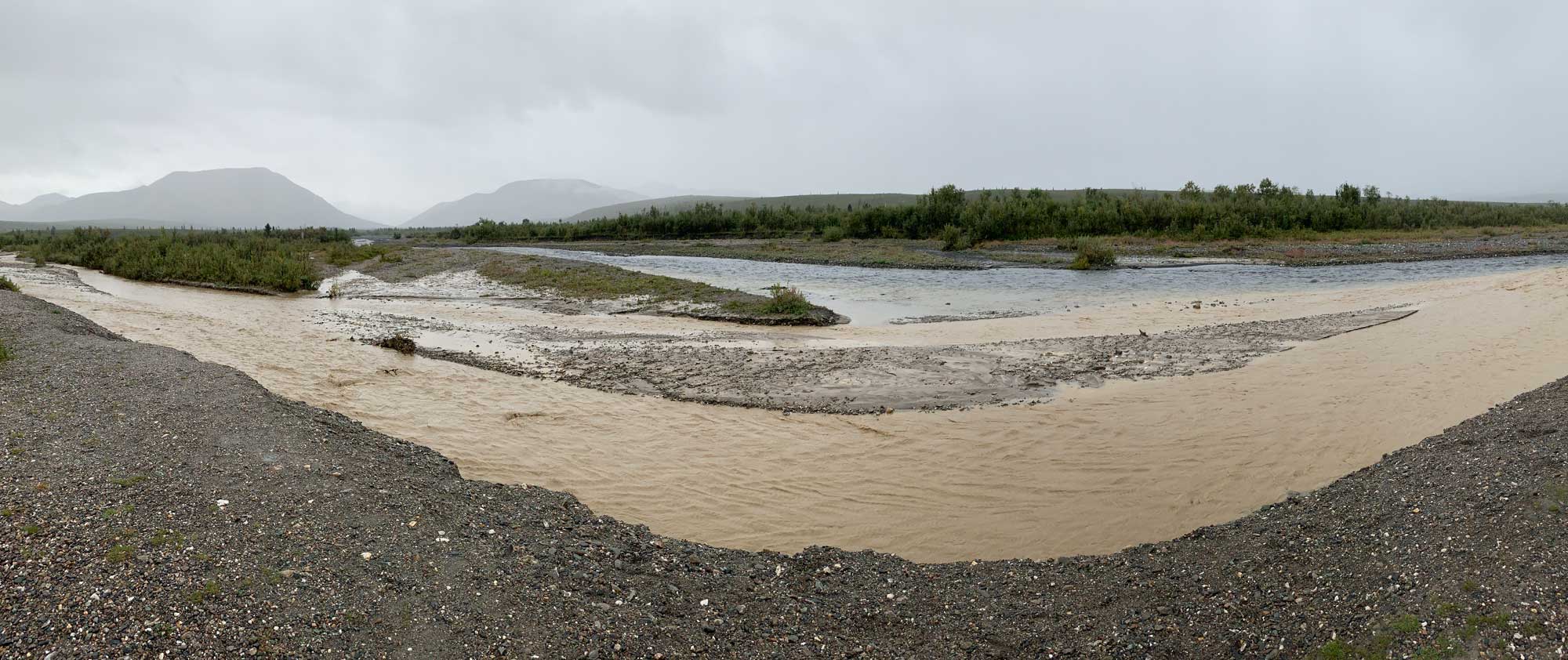 Photograph of two streams coming together in Denali National Park, Alaska. One of the streams is brown because of the large amount of sediment it is carrying.