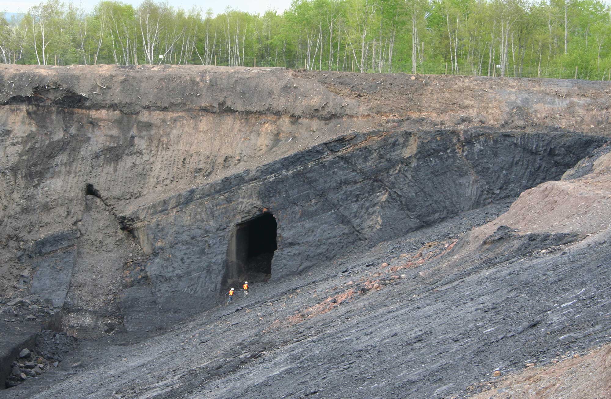Photograph of a thick coal seam with the entrance to a mine shaft cut into it.