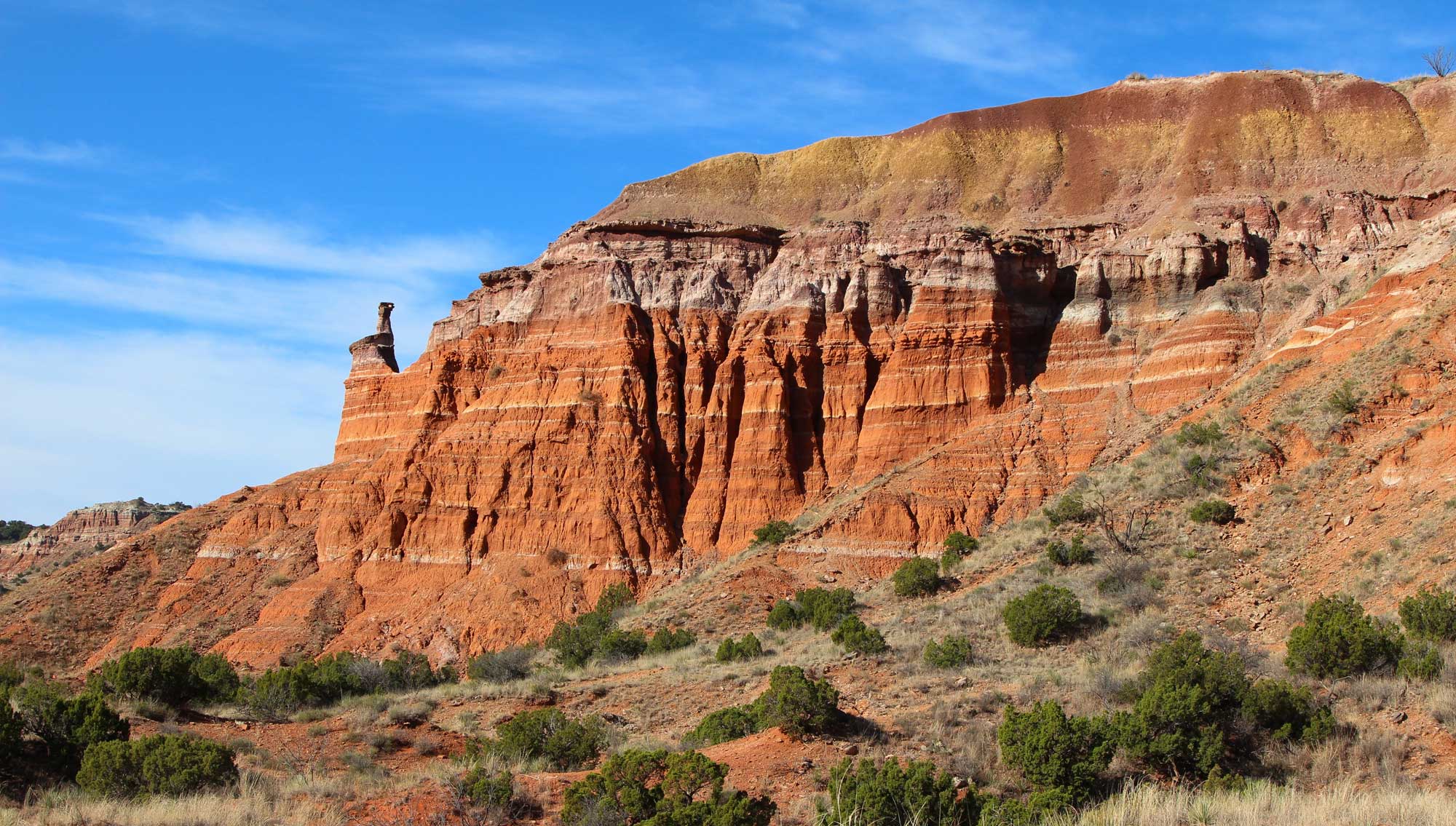 Photo of an outcrop in Palo Duro Canyon, Texas. The outcrop is made up mostly of Triassic-aged red rock.