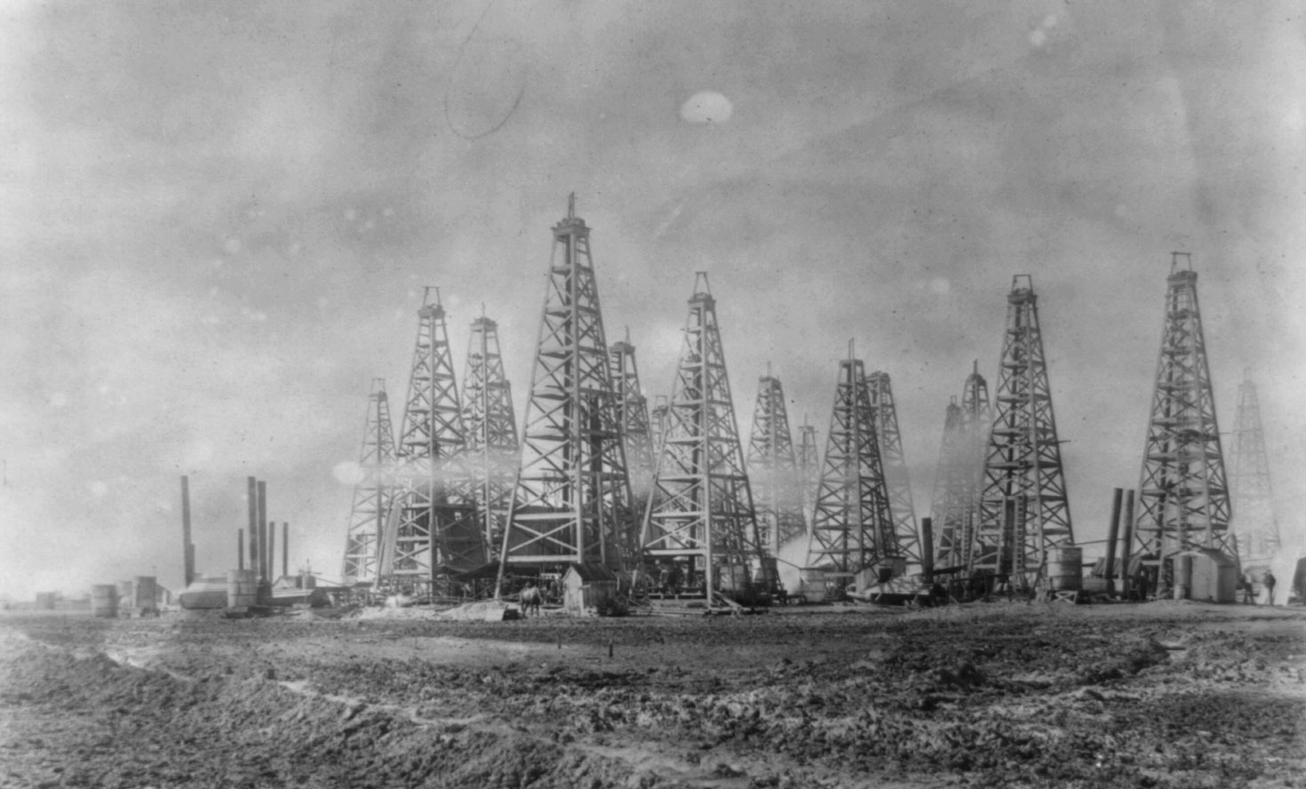 Black-and-white photograph of Spindletop oil field, Beaumont, Porter Arthur, Texas, early 1900s. The oilfield has many wooden derricks.
