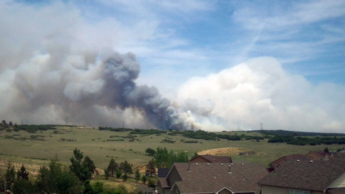 Photograph of smoke rising in the distance behind homes resulting from the 2013 Black Forest Fire in Colorado.
