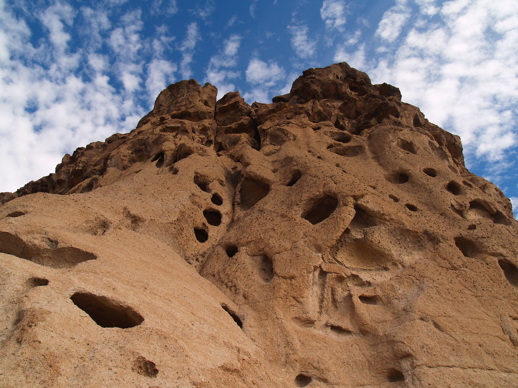 Photograph of a rock wall with numerous holes at "Hole in the Wall" in Mojave National Park.