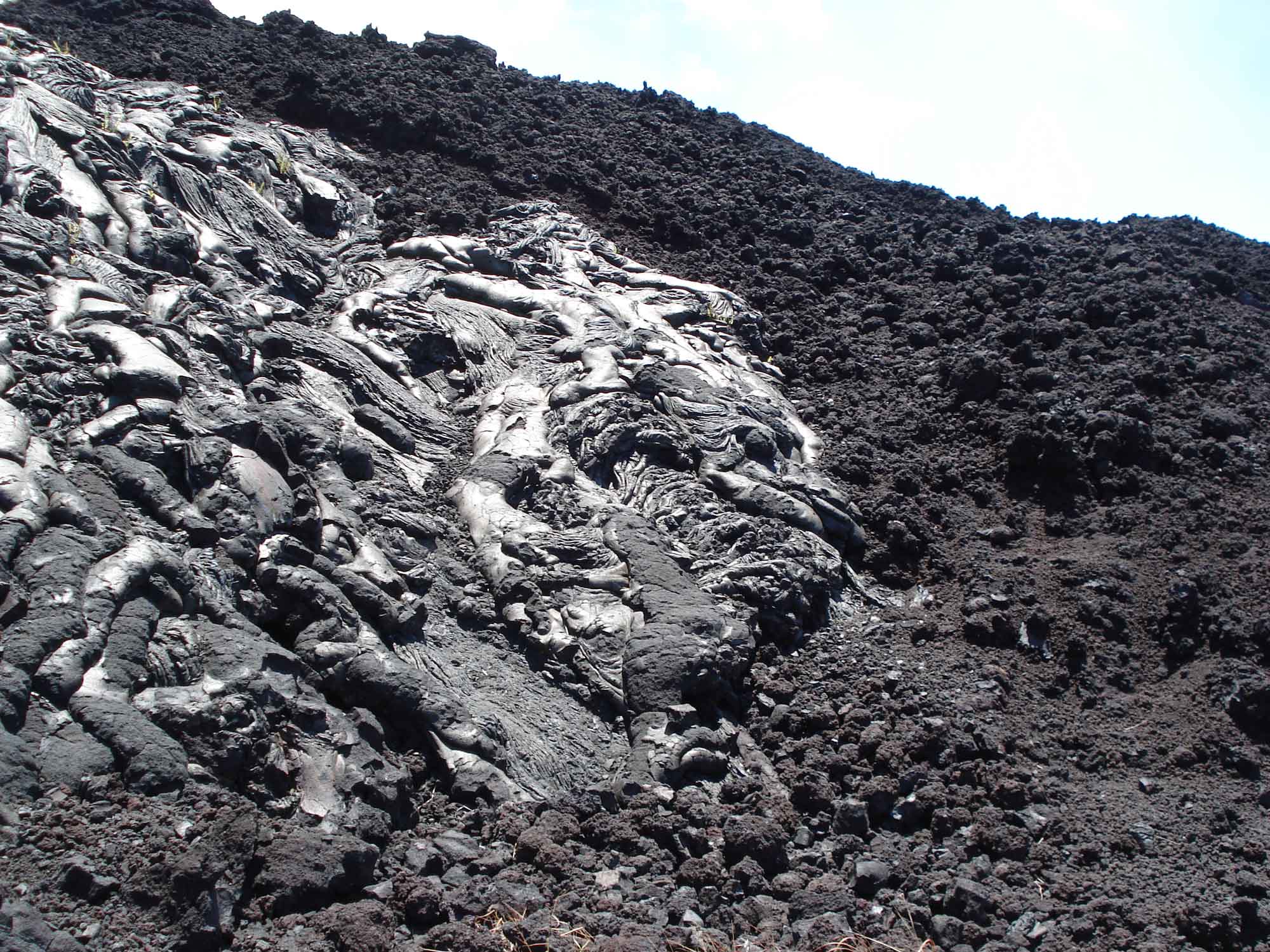 Photograph shows a pahoehoe lava flow next to a ‘a‘a flow.