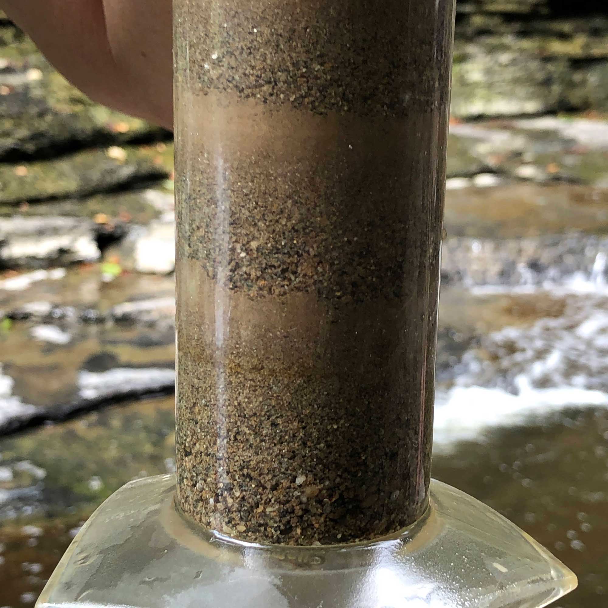 Photograph of a graduate cylinder with layers of sediment inside.