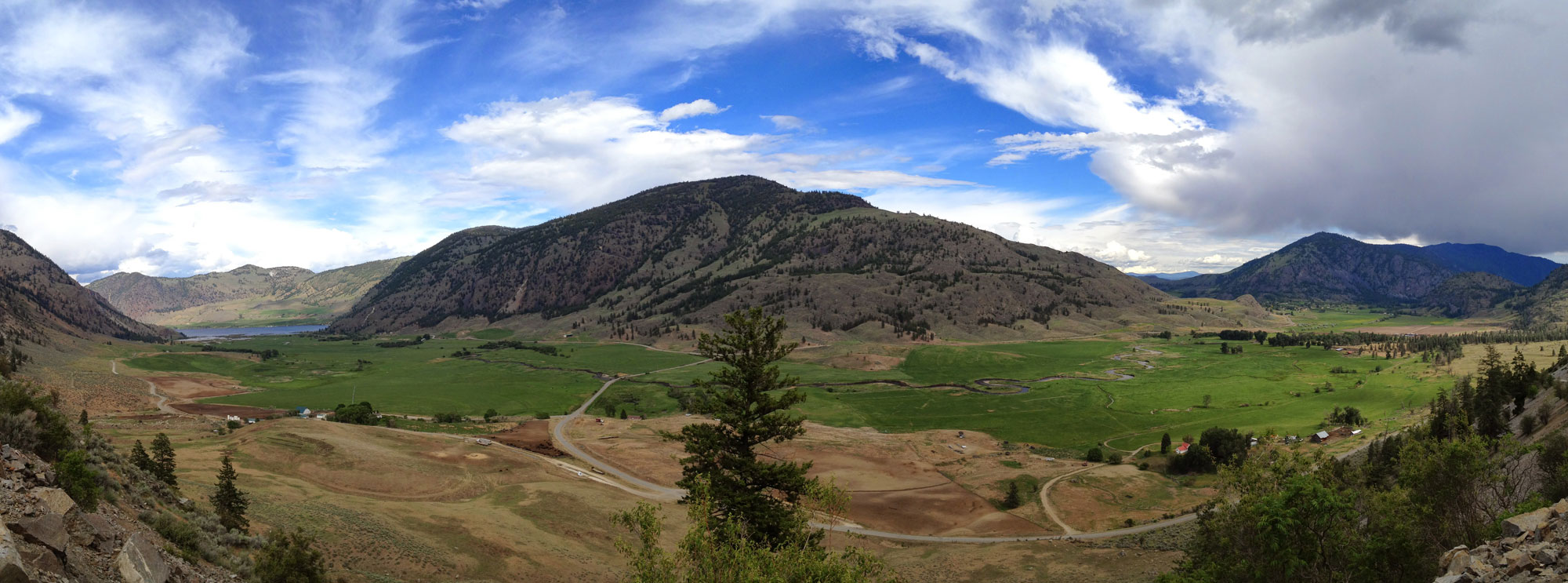 Photograph of Sinlahekin Valley, Okanogan Highlands, northeastern Washington. The photo shows a rounded hill with a river valley at its base. Additional hills rise in the background.