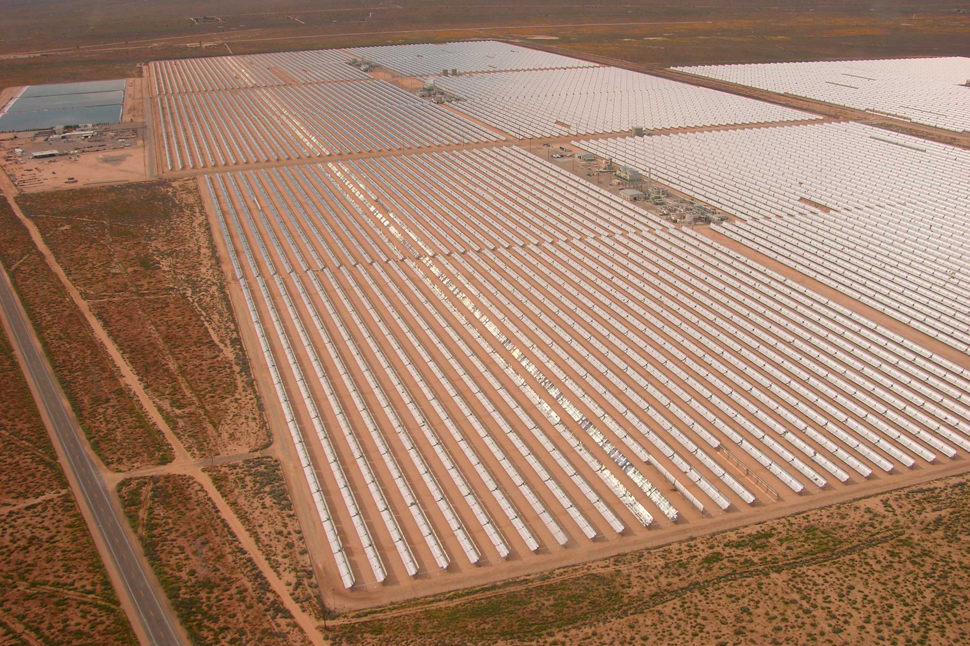 Photograph of a solar farm in the Mojave Desert of California. The image shows rows of solar collectors arrayed on the landscape.