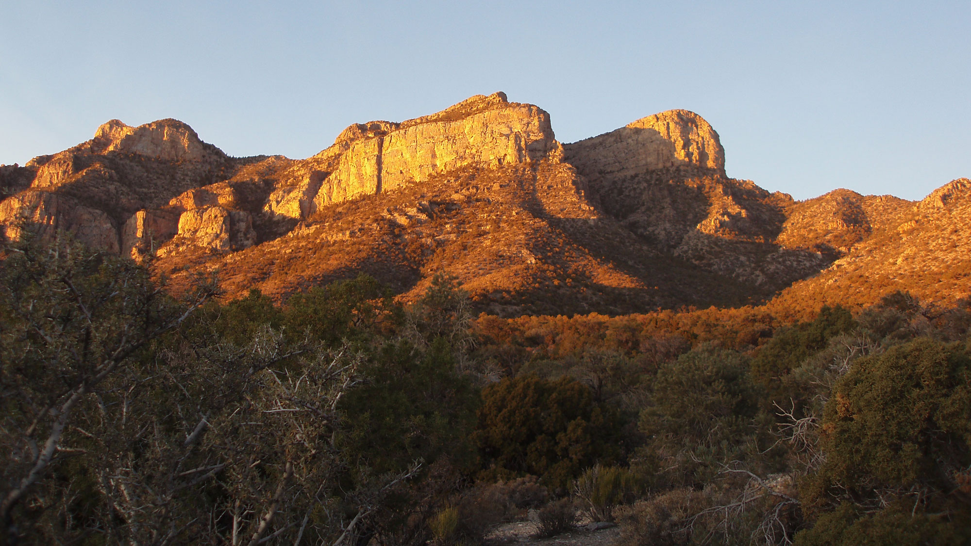 Photograph of the Worthington Mountains in the basin and range of Nevada. The photo shows peaks with a thick cap of rock tilting downward toward the left. The image was taken at sunset.