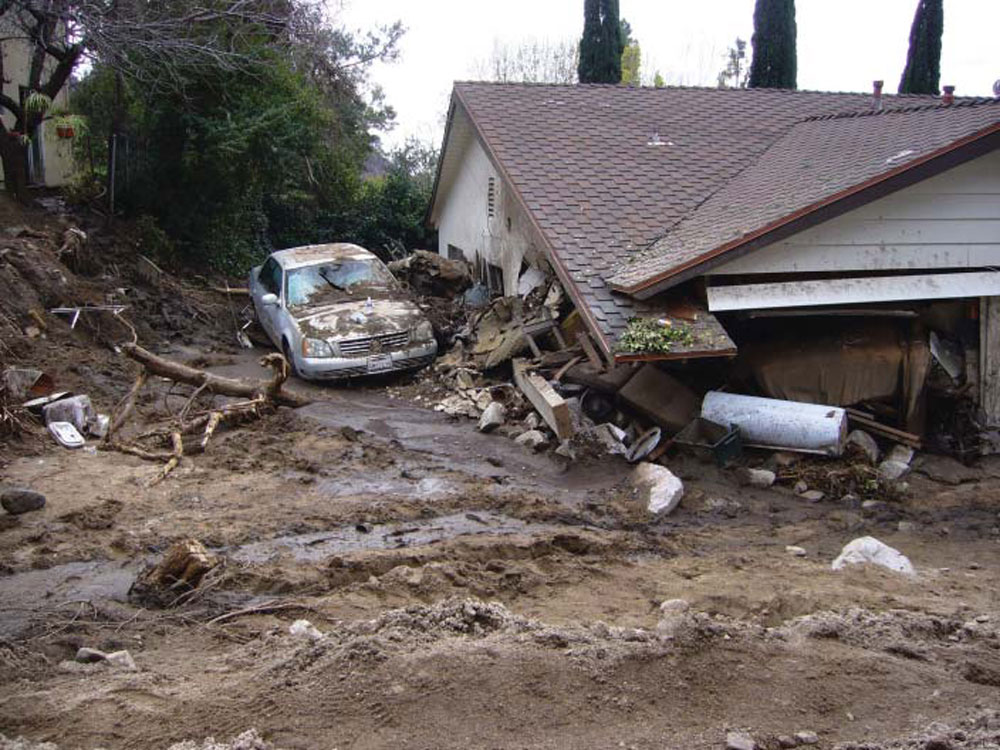 Photograph of a house in California that has been partially buried by a debris flow.