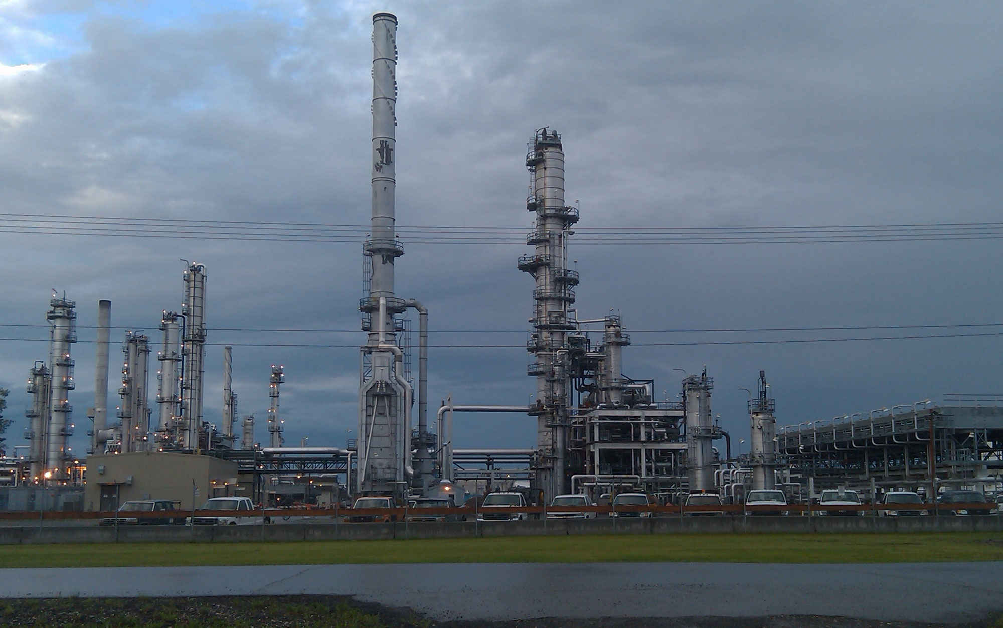 Photograph of an oil refinery near Fairbanks, Alaska. The photo shows structures of the refinery with trucks parked in a parking lot in the foreground. This refinery was closed in 2014.