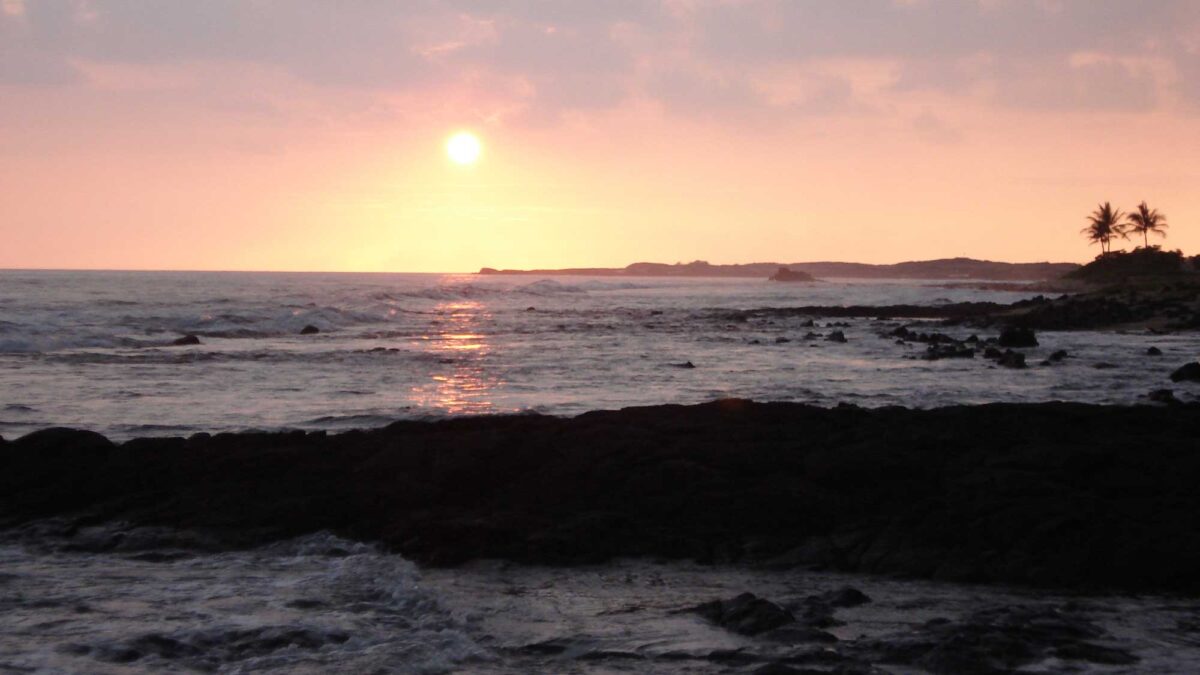 Photograph of the sun setting on a beach near Kona International Airport, Hawaii.