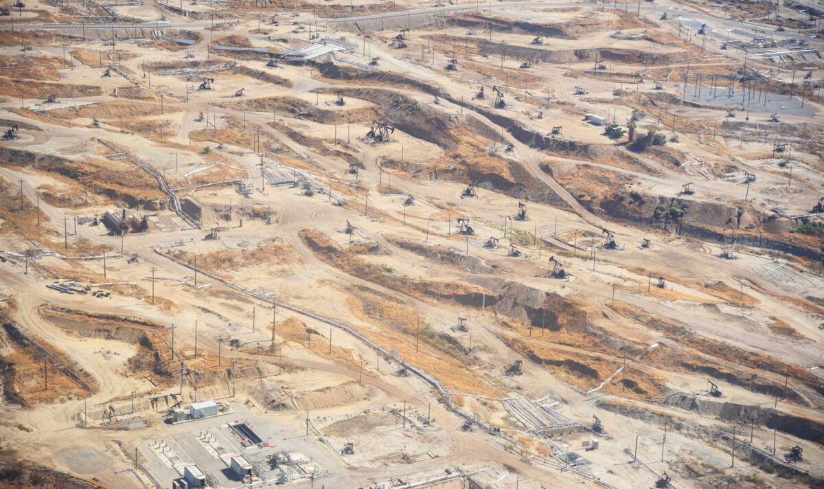Aeiral photograph of the Kern River Oil Field in California. The photo shows a dry landscape heavily dotted with pumpjacks, power poles, and other structures related to petroleum extraction. 