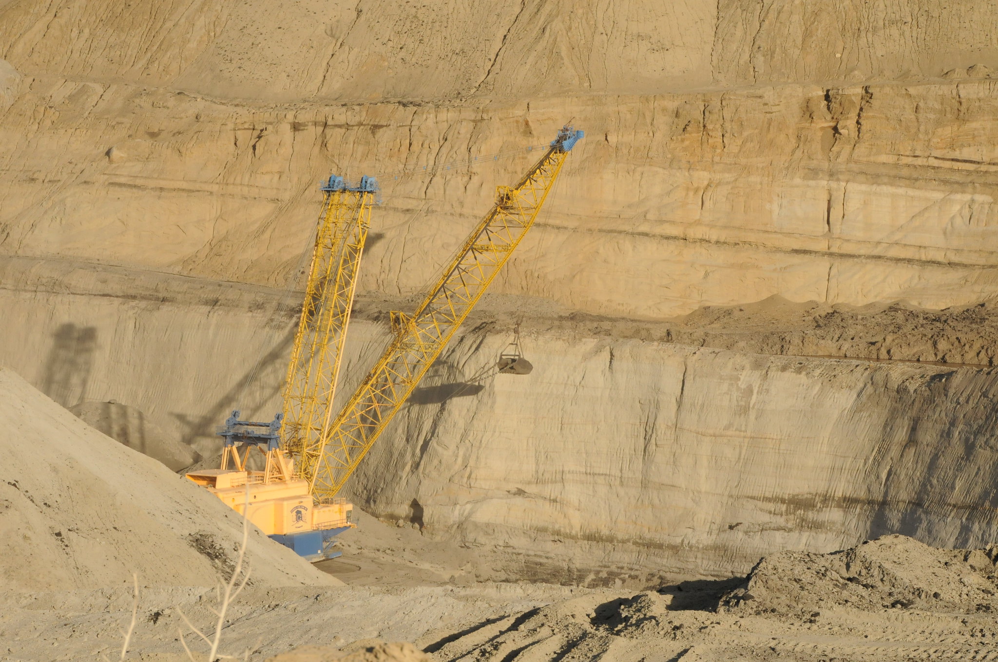 Photograph of a dragline in the Usibelli Coal Mine, Healy, Alaska. The photo shows a machine that looks similar to a crane with a bucket suspended off the end that is used to dig coal.