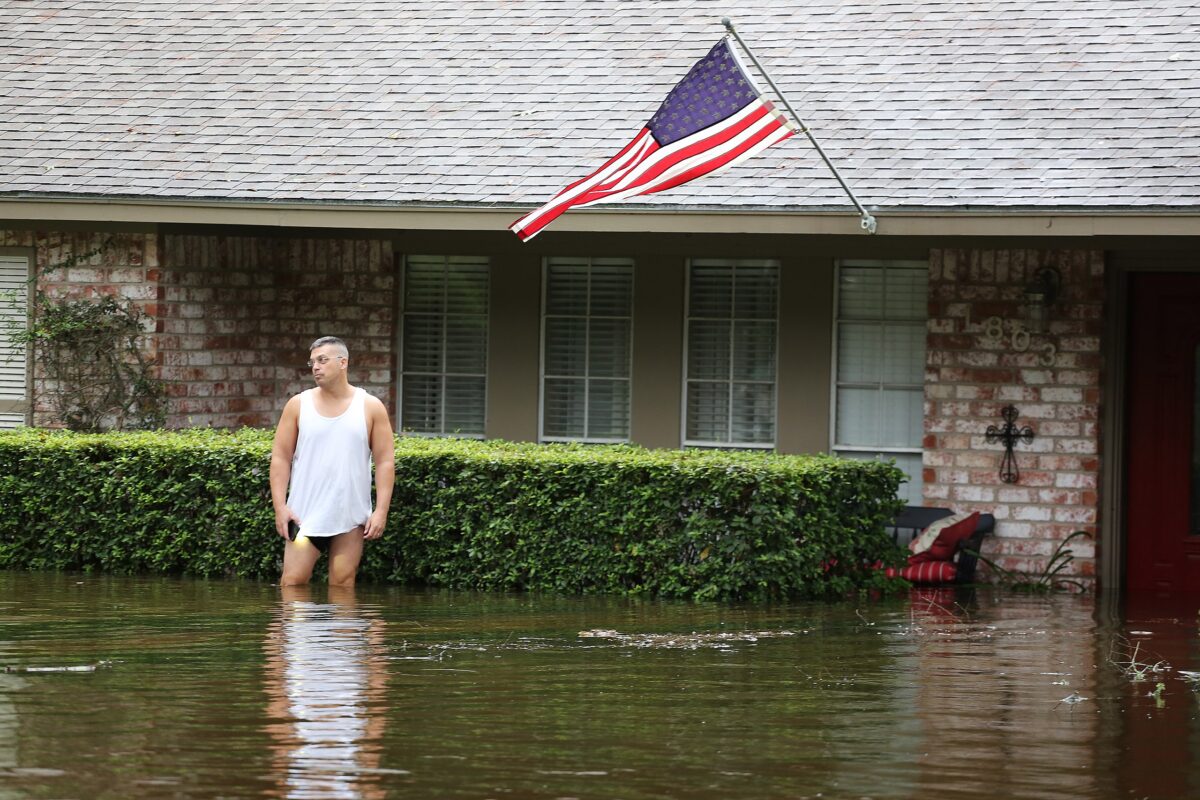 Photo of man standing in floodwater outside a house after Hurricane Harvey