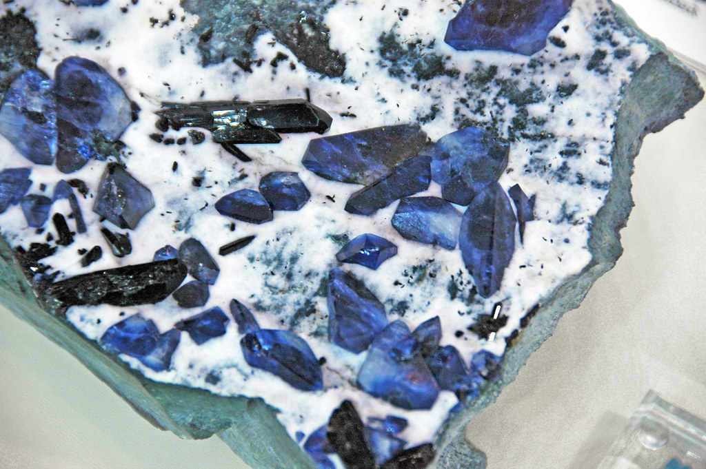 Photograph of a rock sample with crystals of benitoite in a matrix of blueschist.