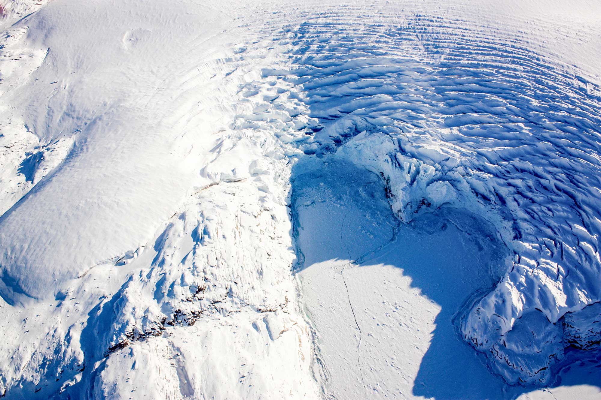 Photo of the edge of a glacier flowing into the sea on the margin of Greenland. The photo shows calving at the edge of the glacial margin.