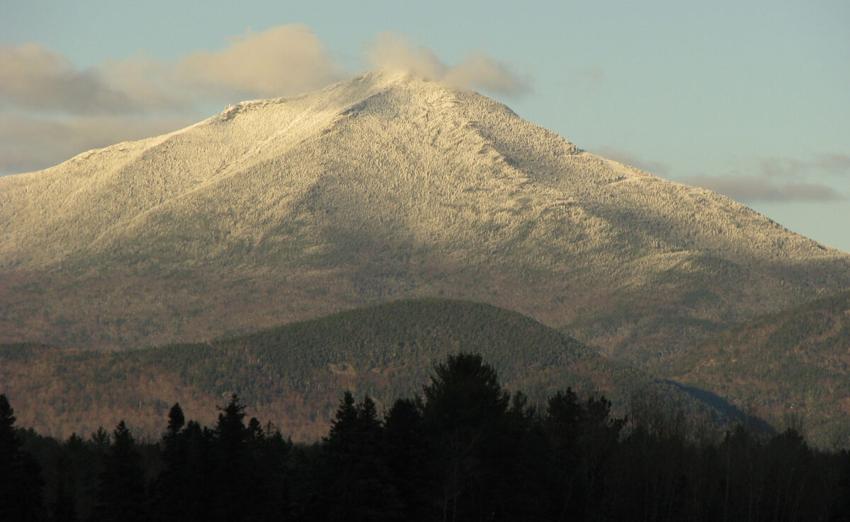 Photograph of Whiteface Mountain, Adirondack Mountains, New York. The photo shows a triangular mountain peak lightly dusted with snow.