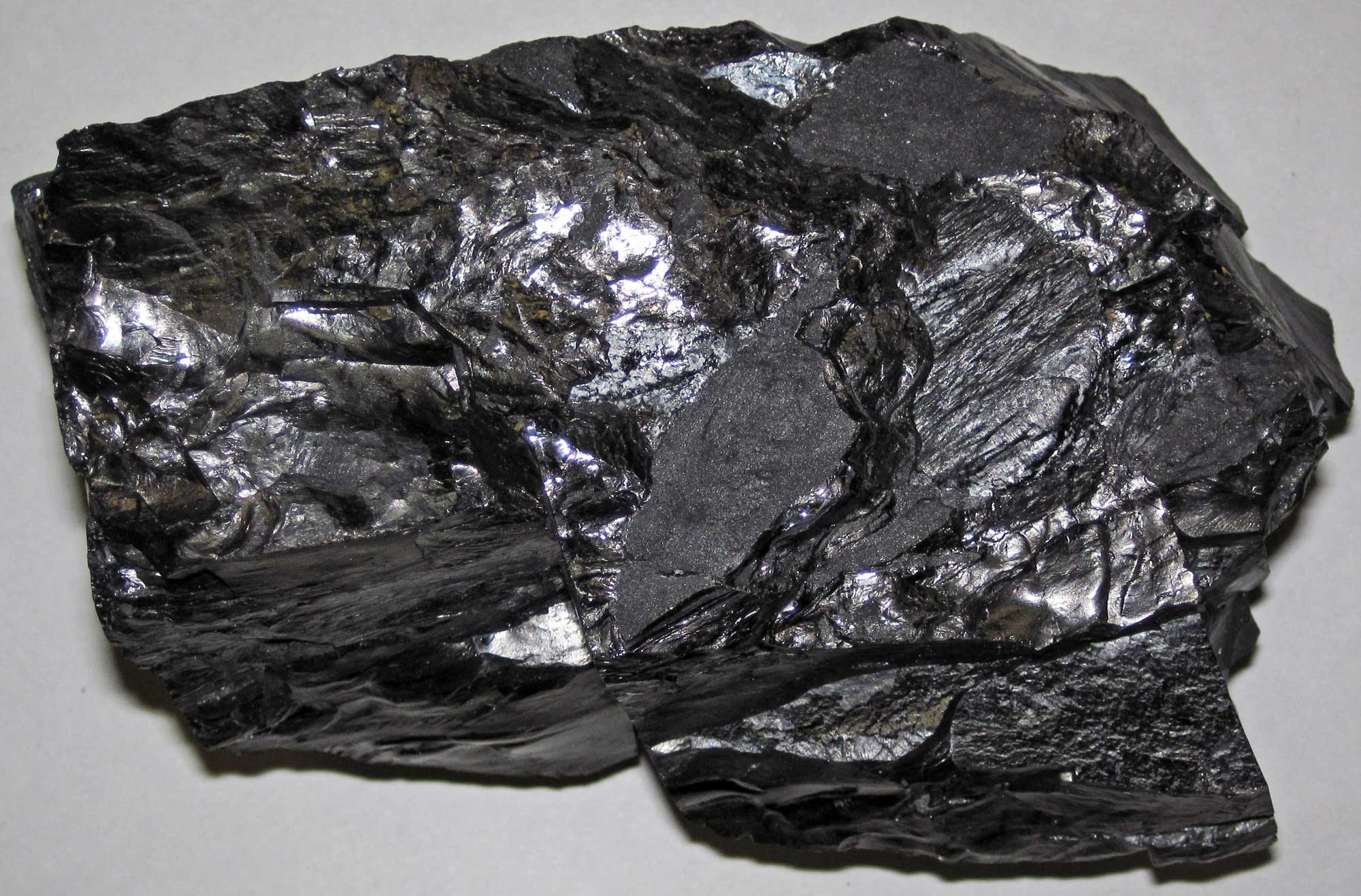Photograph of a chunk of anthracite coal. The chunk of coal is roughly rectangular, shiny, and black.