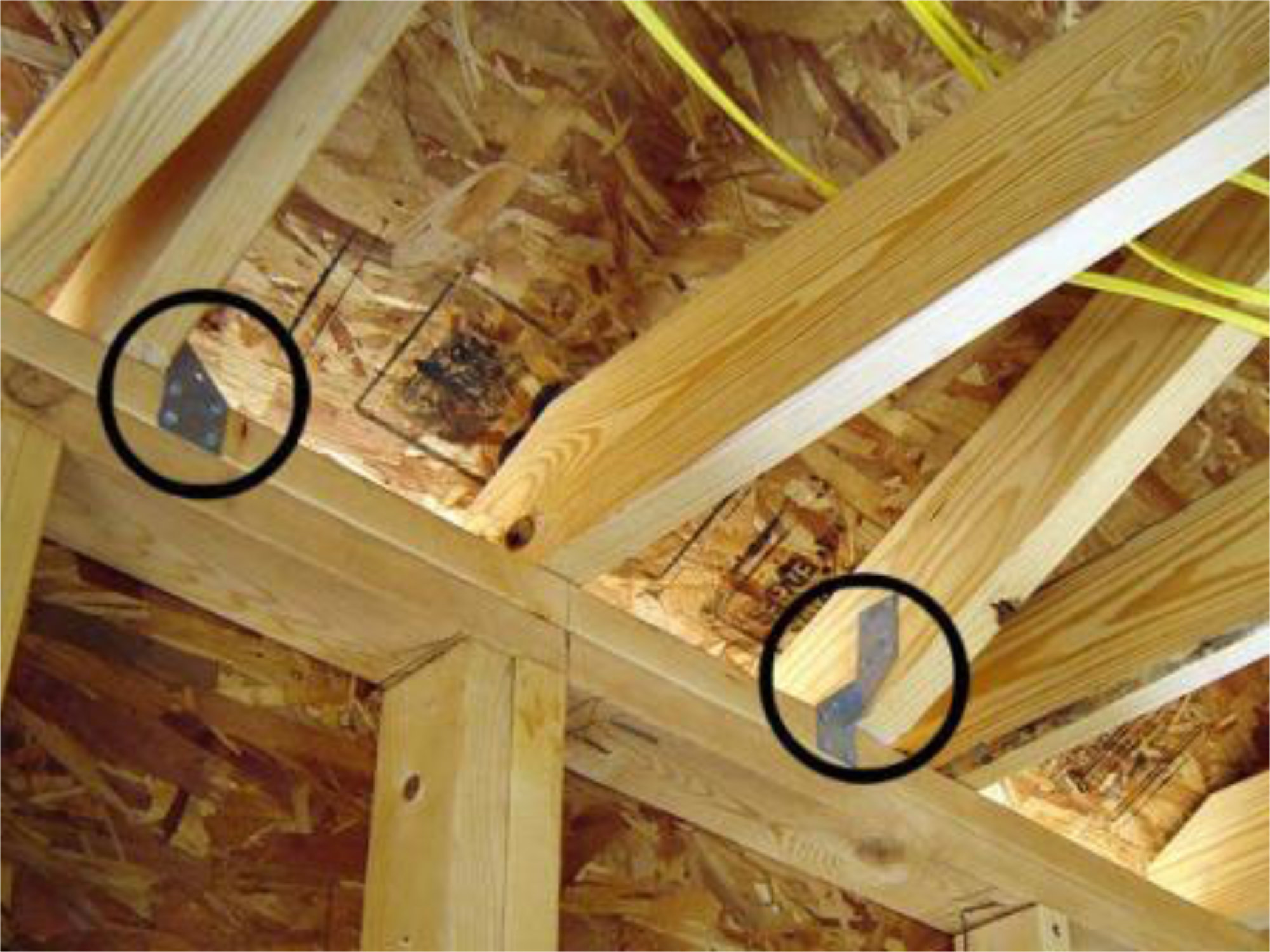Photo of the interior structure of a roof, with wood joists held together with hurricane clips.