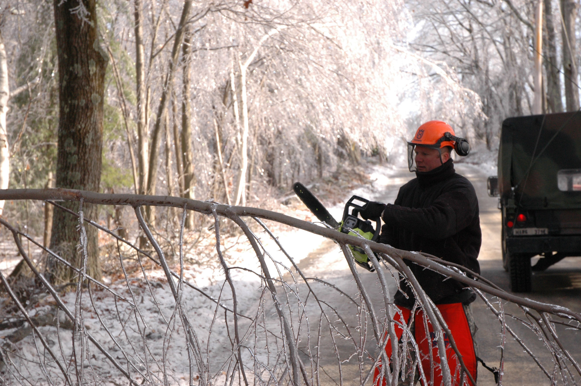 National Guard member cuts icy tree limb following a winter storm.