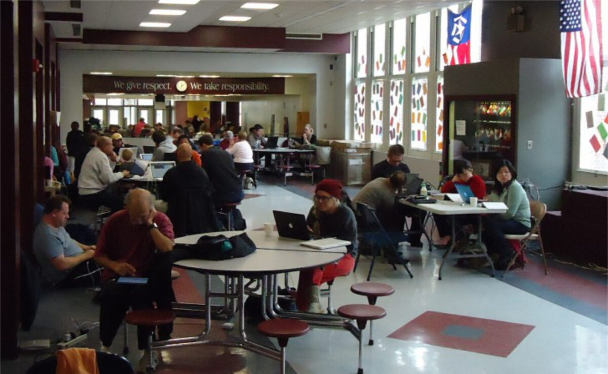 Photo of people sitting in a middle school used as a shelter following Hurricane Sandy