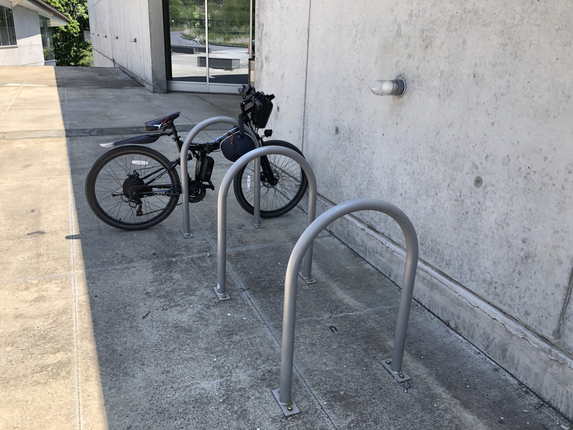 Photo of a bicycle attached to a bike rack outside a building.