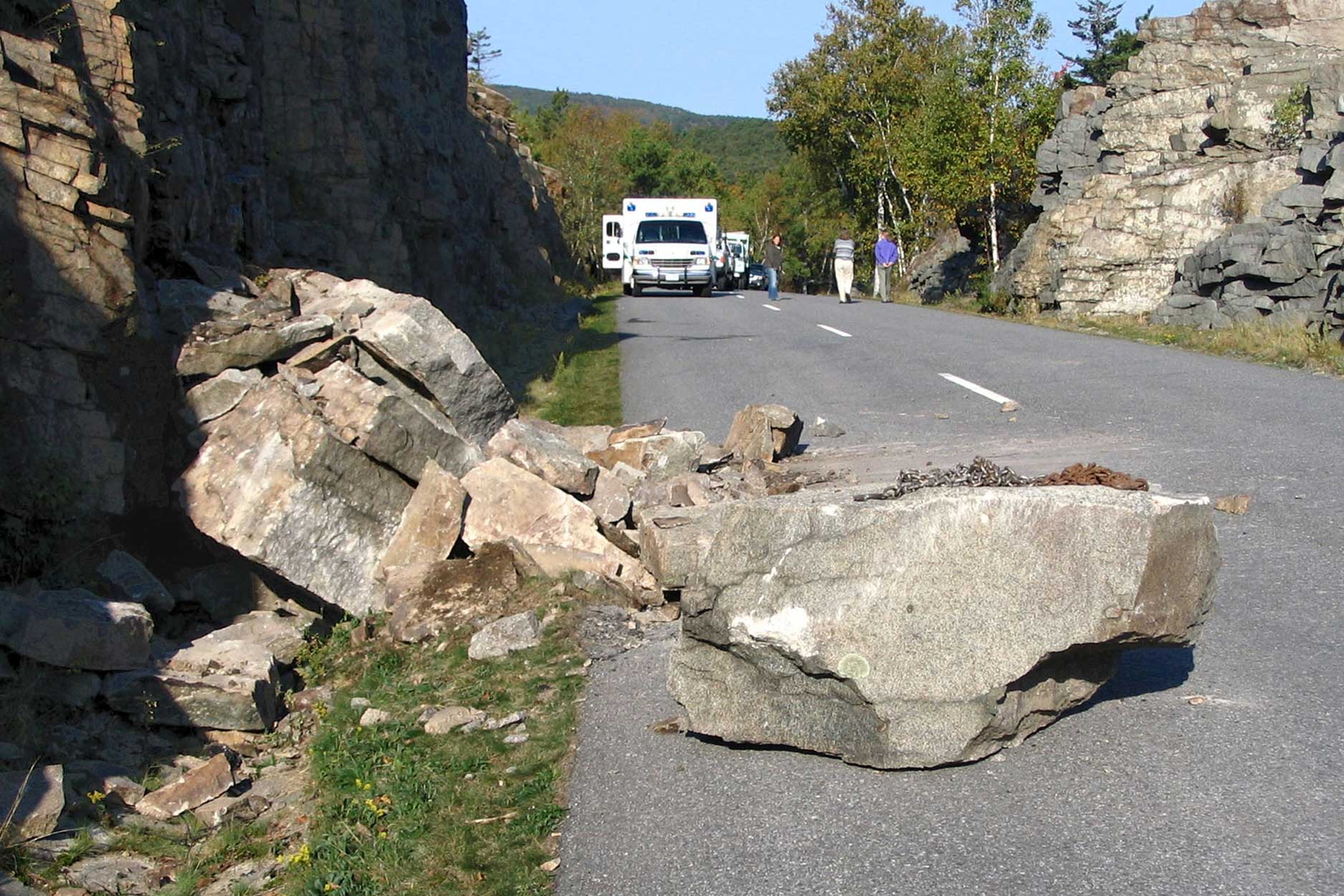 Photograph of a rockfall at Acadia National Park in Maine. The photo shows rocks that have fallen into one lane of a two-lane paved road.