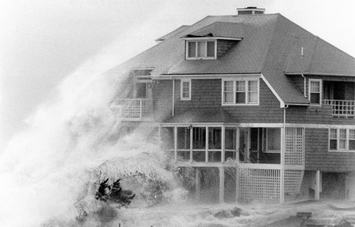 Black and white photograph of waves lashing a house in Gloucester, Massachusetts during a storm in 1991.